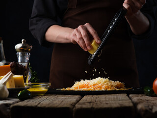 the chef prepares by rubbing cheese for pasta. Different types of cheese. The concept of cooking dishes with cheese. Cooking and restaurant business, menu