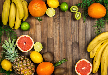 pieces and whole tropical fruits on a wooden background. fresh tasty citrus fruits. space for text 