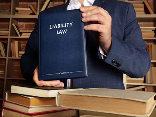 Lawyer holds LIABILITY LAW book. Legal liability concerns both civil law and criminal law and...