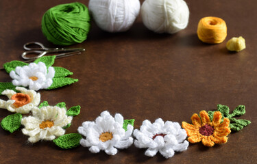  Dark blurred background of crocheted flowers and leaves close up with working space.  