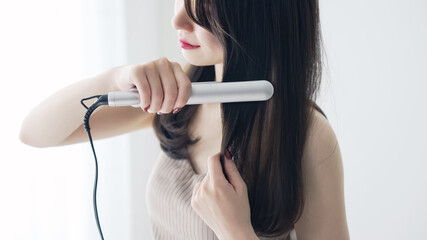 ヘアアイロンを使う女性　スタイリング