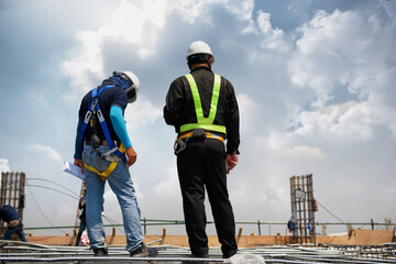 Construction Engineers with foreman doing to check or inspection on top of highrise building at building construction site.