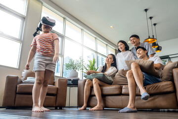 happiness asian family multi age generation enjoy watch and cheering her daughter up playing vr goggle together with fun and exited in living room home interior background quarantine weekend