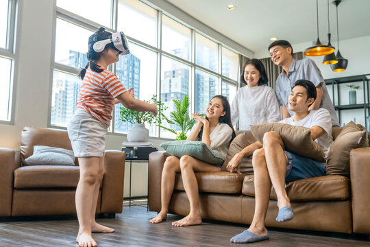 happiness asian family multi age generation enjoy watch and cheering her daughter up playing vr goggle together with fun and exited in living room home interior background quarantine weekend