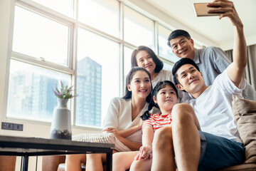 asian multi generation family parent and grand parent with little daughter child sit relax on sofa...