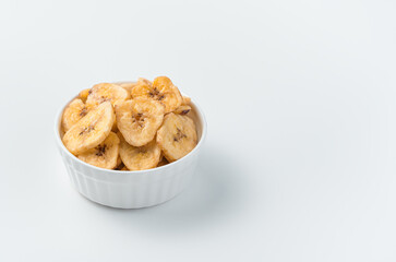 Healthy sweets, pieces of dried banana in a bowl on a light background.