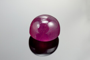 Natural heated, treated, lead glass filled, oval cabochon pink ruby (corundum Al2O3) Madagascar. Details, micro cracks, bubbles, inclusions, glass flux flow. Close-up details macro photo. Reflections.