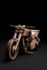 Fototapeta na wymiar Toy motorcycle made of plywood on a black background