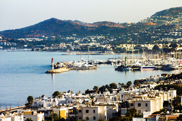 Panorama of the Bay of Turgutreis Center with Marina, sealights and city at a hot midday with calm sea.