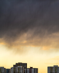Dark rain clouds over city buildings ar sunset

