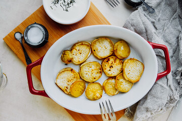 round slices baked red sweet potatoes in red ceramic baking dish, spices, salt, pepper, white cream sauce. process cooking homemade food. yam recipes, food content, life atmosphere, selective focus