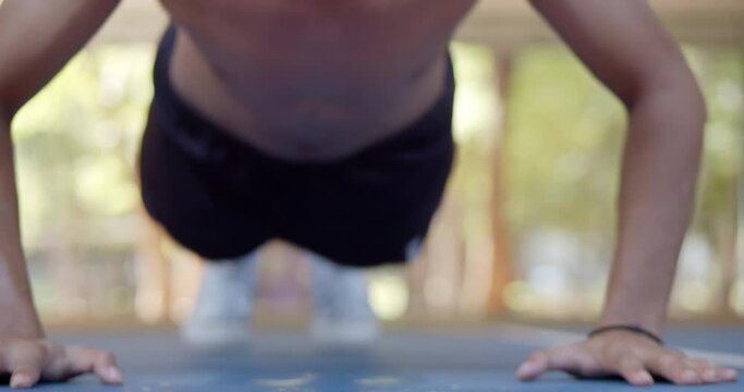 Shirtless Asian teenage man doing push-ups to exercise until he sweats.