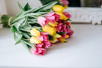 Close up Fresh spring yellow and pink tulips bouquet on white wood table background in mirror with copy space for text. Love, easter, International Women day, Mother and Happy Valentine day concept