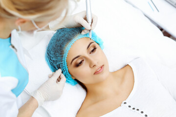 Professional beautician doing eyebrow tattoo at woman face. Permanent brow makeup in beauty salon, closeup. Cosmetology treatment