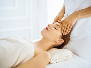 Beautiful woman enjoying facial massage with closed eyes in spa center