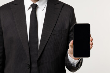 Close up cropped photo portrait shot young employee business corporate man in classic formal black suit shirt work in office hold mobile phone blank screen workspace area isolated on white background.