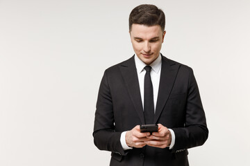 Young employee business corporate lawyer man wearing classic formal black grey suit shirt tie work in office hold mobile cell phone chat online browsing isolated on white background studio portrait