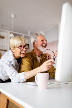 Senior woman helping senior man to use computer