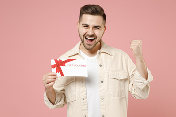 Young satisfied overjoyed fun happy rich man 20s wearing jacket white t-shirt holding gift voucher...
