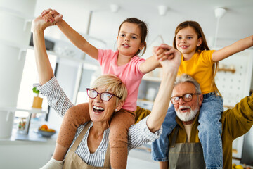 Portrait of happy elderly couple and grandchildren playing together