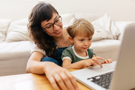 Cute kid learning using laptop with mother