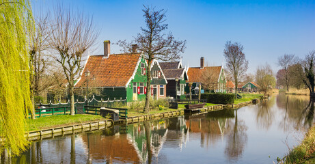 Fototapeta na wymiar Traditional dutch wooden houses reflected in the canal in Zaanse Schans, Netherlands