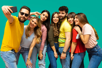 Seven smiling young friends taking a selfie together- group of kids isolated on light blue background