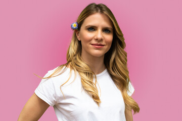 Beautiful blond hair model face portrait. beautiful girl wearing a white shirt and a lavender flower in her hair -.single subject looking at the camera on pink background