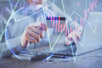 Double exposure of man hands holding a credit card and Forex graph drawing. Stock trading and digital fintech in Internet E-commerce concept.