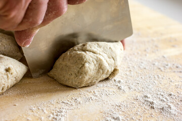Rye flour bread baking dough and dough cutting knife in hands, close-up, home baking, authentic hobby