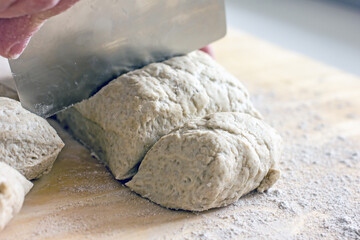 Rye dough for baking bread and knife for cutting dough on wooden background, close-up. Authentic hobby home baking