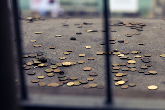 Close up of some yellow coins thrown behind bars, for good wishes.Zlotis and Euros.