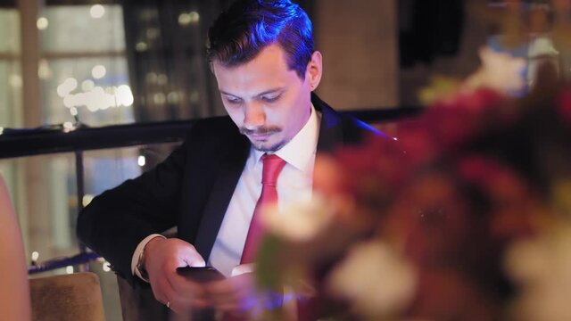 Focused business man in tie suit chatting surfing internet use smartphone night party festive event
