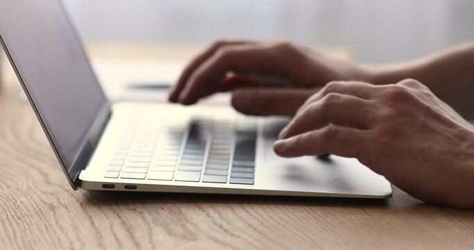Close up male hands typing on computer keyboard. Young man texting message in social network, web surfing information, choosing goods online or working distantly on laptop, using software apps.