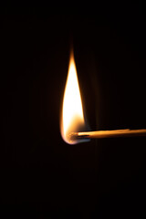 Nahaufnahme eines brennenden Streichholzes, dunkler Hintergrund