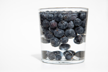 Crockery with juicy and fresh blueberries on white table.Close up portrait of fresh blueberries in a glass bowl on white background