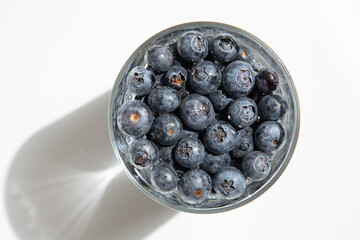 Close-up of blueberries in a transparent bowl, on white background.Fresh raw organic farm blueberry in a cup.