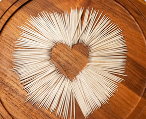 toothpick on dark wooden background in circle composition with heart