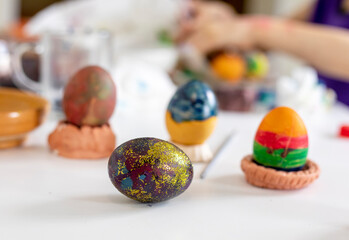 Fototapeta na wymiar purple easter egg with glitter on the background of painted eggs, preparation for the holiday