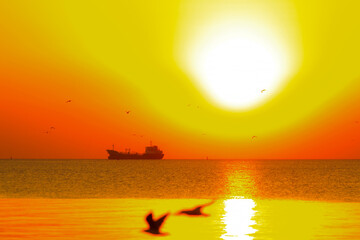 Fototapeta na wymiar Sunset or evening time with golden sky at sea or ocean with cargo ship and seagull bird flying at Bang poo, Samutprakan, Thailand.