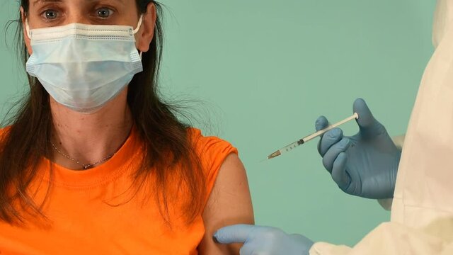 Doctor doctor injects vaccine with syringe against covid19 coronavirus. Cyan background