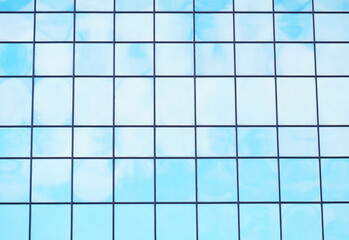 Reflection of the blue sky with clouds in the stained glass windows of the business office.