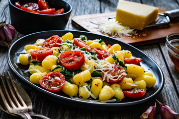 Gnocchi with tomato, spinach and parmesan  on wooden table
