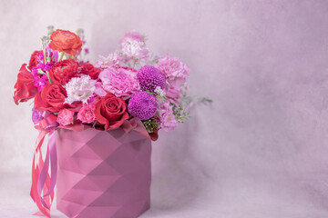 Round paper box vase with geometric pattern with lush bouquet of red, light pink, purple, white cute delicate small roses of different sizes, flowers. Place for text