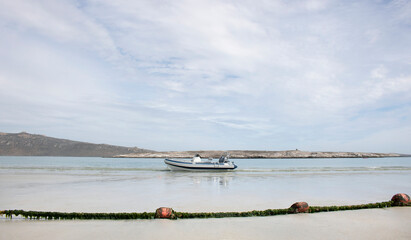 Langebaan Lagoon, South Africa. A Beautiful tourist destination with rocky coastline and speed boat on shore with fishing net.