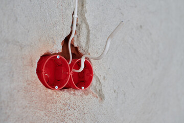 Plastic socket box and electrical wires on plastered wall