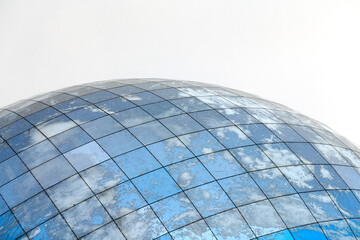 Glass spherical modern building with reflection of blue sky