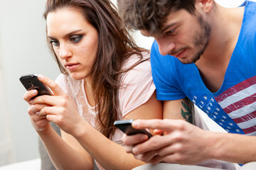 Young couple engrossed in using their mobile phones