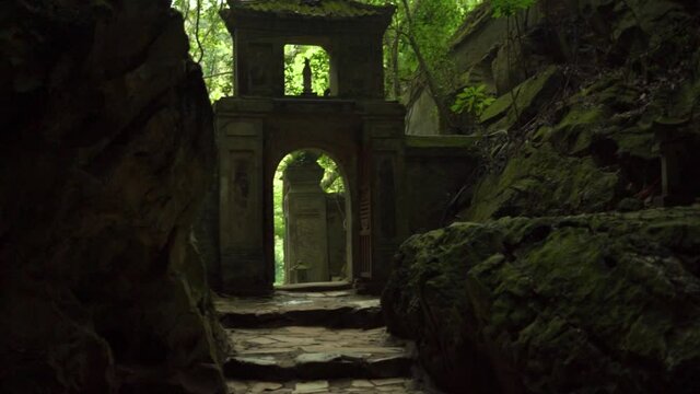 Ancient stone arch and steps in passway between large mountains near entrance to famous marble caves near city Da Nang in Vietnam.