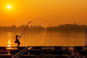 Asian men are using nets to fish in the Mekong River. Fishermen raising nile tilapia, floating cages on the Mekong River. Nongkhai, Thailand.